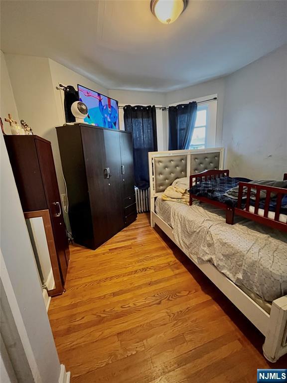 398 Cliff St, Fairview, NJ 07022 - bedroom with radiator and light wood-style floors