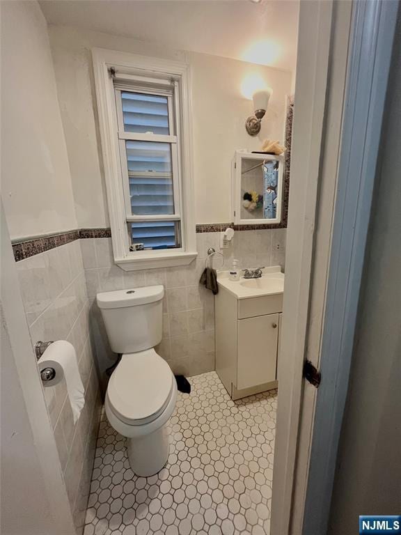 398 Cliff St, Fairview, NJ 07022 - bathroom with toilet, vanity, a wainscoted wall, tile walls, and tile patterned floors