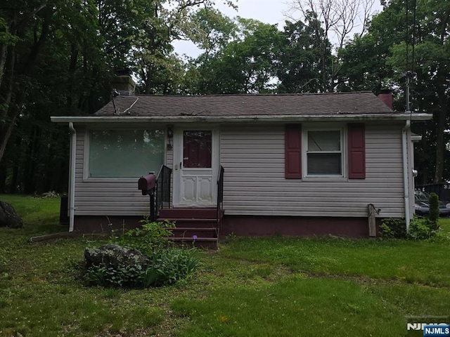view of front of house with entry steps, a chimney, and a front lawn