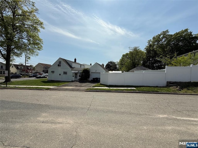 view of front of home with fence, a garage, and a residential view