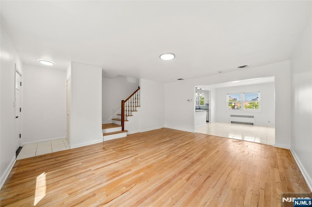 7 Edgewater Pl, Edgewater, NJ 07020 - unfurnished living room with radiator heating unit, stairs, light wood-style floors, and baseboards