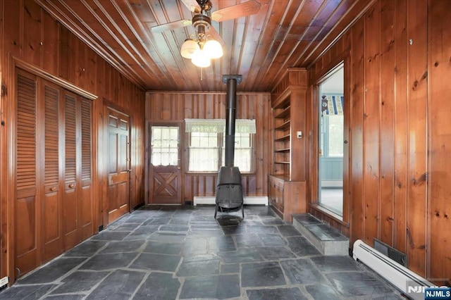 35 Mccosh Rd, Clifton, NJ 07043 - foyer featuring a wood stove, baseboard heating, dark stone finish floors, wood walls, and a ceiling fan