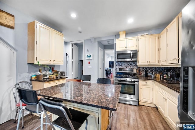 1431 51st St, North Bergen, NJ 07047 - kitchen featuring stainless steel appliances, light wood-style flooring, decorative backsplash, a breakfast bar, and recessed lighting