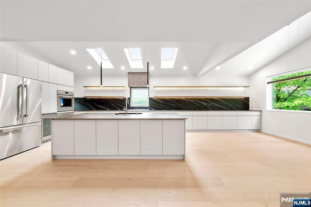 kitchen featuring appliances with stainless steel finishes, a sink, decorative backsplash, modern cabinets, and recessed lighting