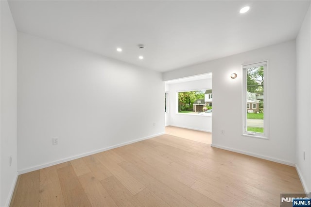 empty room with light wood finished floors, baseboards, and recessed lighting
