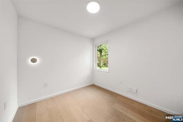 spare room featuring light wood-type flooring and baseboards
