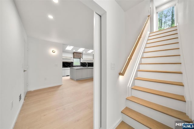 stairs with wood finished floors, baseboards, and recessed lighting