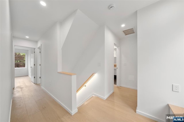 hall featuring an upstairs landing, light wood-type flooring, recessed lighting, and baseboards