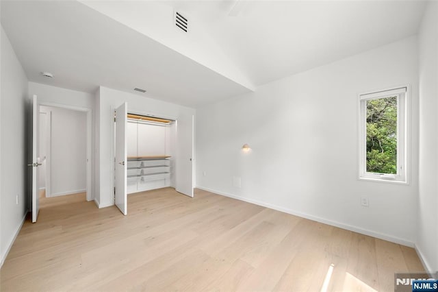 unfurnished bedroom featuring light wood finished floors, baseboards, and a closet