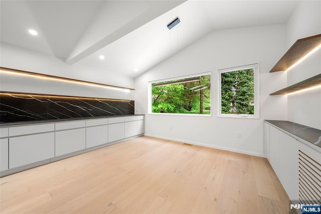 empty room featuring vaulted ceiling, light wood-style floors, baseboards, and recessed lighting