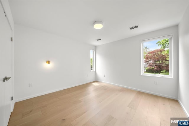 unfurnished room with healthy amount of natural light, light wood-type flooring, and baseboards
