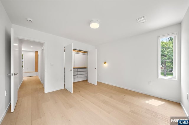 unfurnished bedroom featuring light wood finished floors, baseboards, and a closet