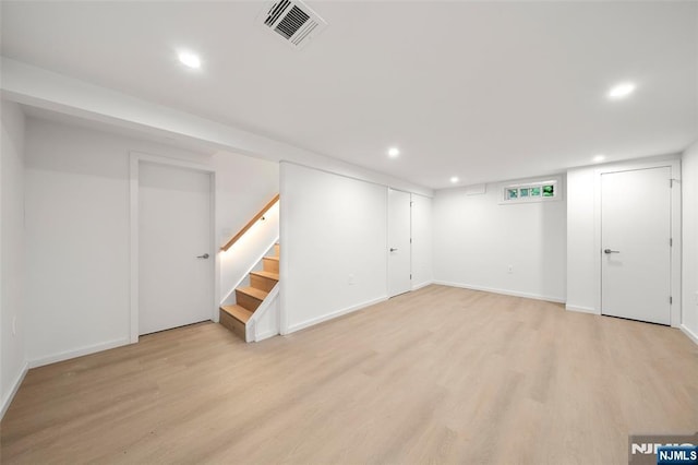 finished basement featuring light wood-style floors, recessed lighting, stairway, and baseboards