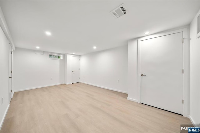 finished below grade area with recessed lighting, light wood-type flooring, and baseboards