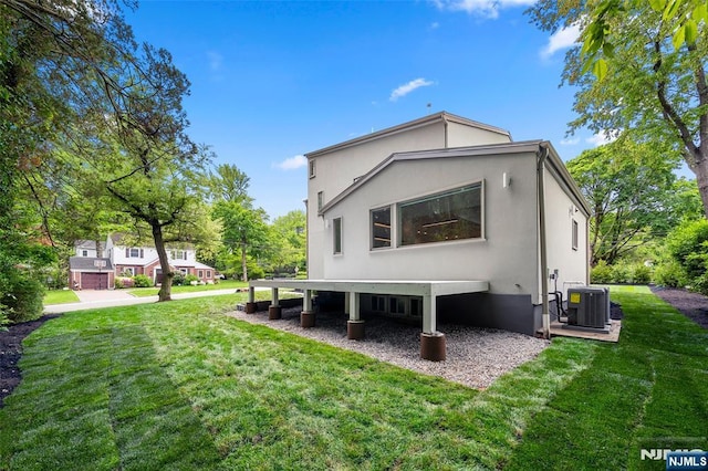 back of property featuring cooling unit, stucco siding, and a yard