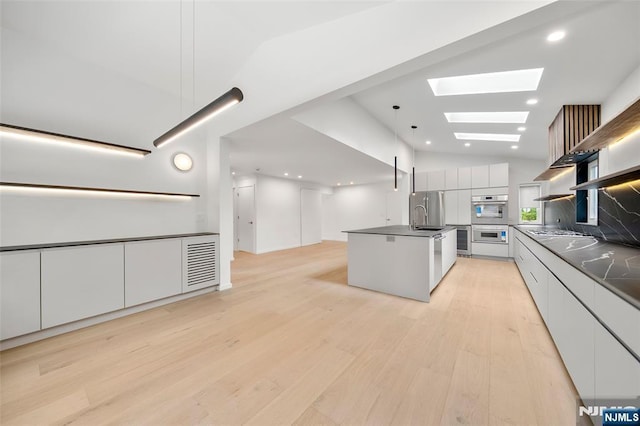 kitchen with modern cabinets, dark countertops, lofted ceiling, a skylight, and light wood-type flooring