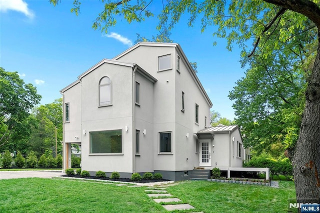 view of front of property with stucco siding, a standing seam roof, a front lawn, and metal roof