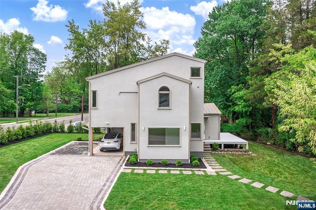 rear view of property featuring decorative driveway, a yard, a standing seam roof, stucco siding, and a carport