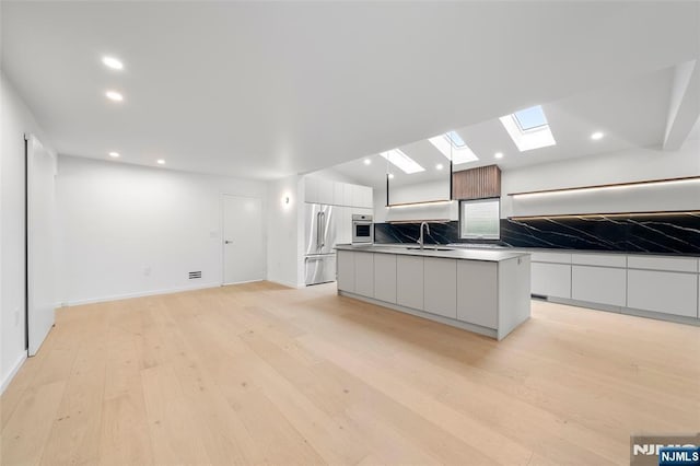 kitchen with modern cabinets, stainless steel appliances, a sink, white cabinetry, and recessed lighting