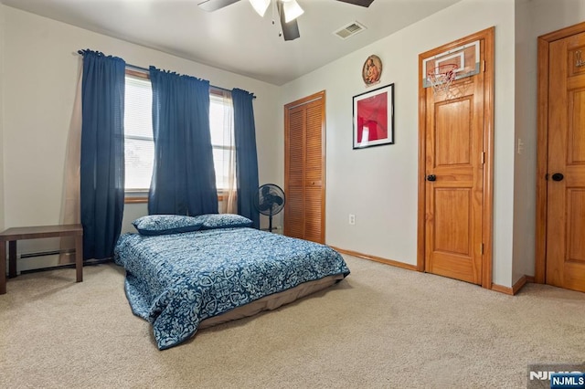 carpeted bedroom with a closet, baseboards, a ceiling fan, and a baseboard heating unit