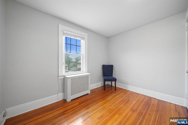 unfurnished room with radiator heating unit, baseboards, and light wood-type flooring
