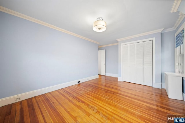 unfurnished bedroom featuring a closet, baseboards, ornamental molding, and light wood-style flooring