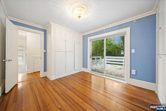 spare room with wood finished floors, ornamental molding, and baseboards