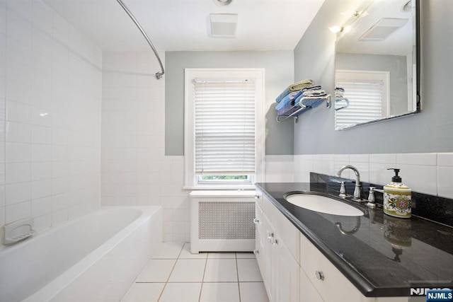full bath featuring radiator heating unit, tile walls, tile patterned flooring, vanity, and a wainscoted wall