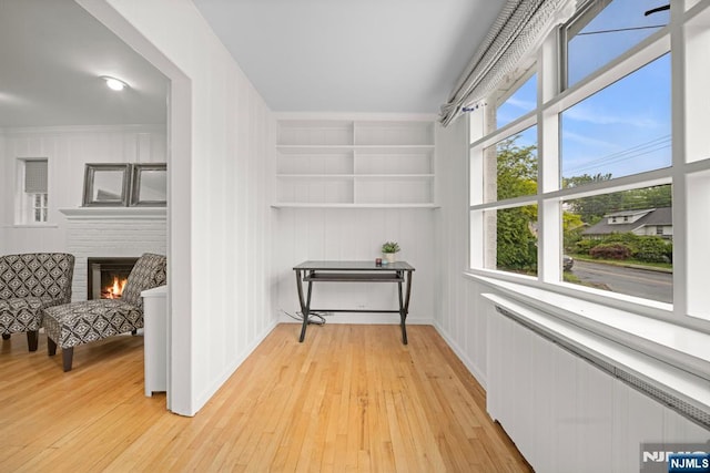 sitting room featuring radiator heating unit, light wood finished floors, and built in features