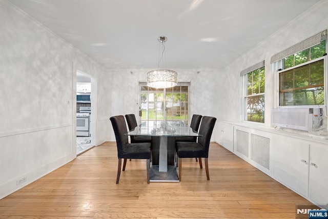 dining space with a chandelier, ornamental molding, and light wood-type flooring