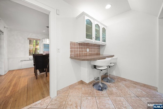 bathroom with decorative backsplash and lofted ceiling