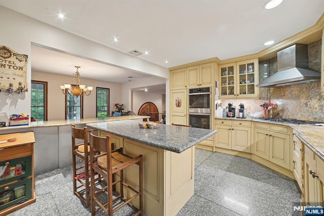 41-21 Dunkerhook Rd, Fair Lawn, NJ 07410 - kitchen featuring cream cabinetry, wall chimney exhaust hood, stainless steel appliances, a breakfast bar area, and recessed lighting