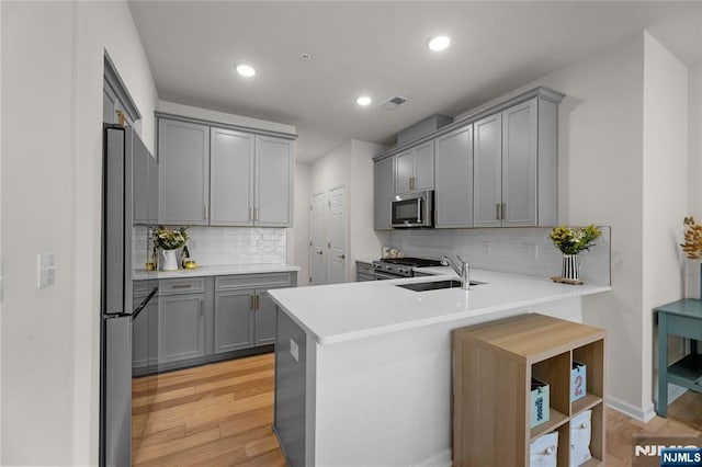 11 Arnold Dr, Wood Ridge, NJ 07075 - kitchen featuring gray cabinetry, stainless steel appliances, decorative backsplash, a peninsula, and light wood finished floors