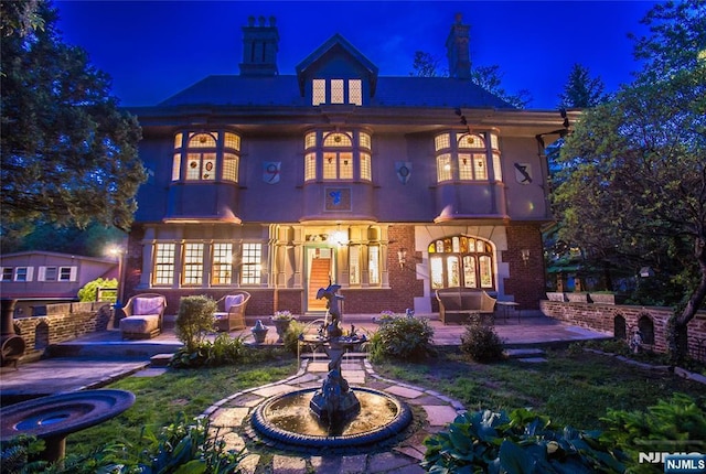 back of house at night featuring a patio and french doors