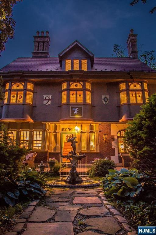 back of house at twilight with a chimney