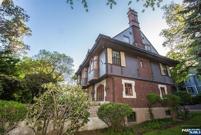 view of home's exterior with brick siding, stucco siding, and a chimney