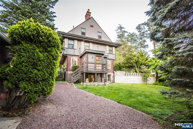 rear view of property featuring stairs, stucco siding, a chimney, and brick siding