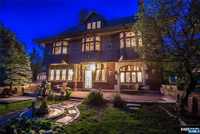 back of house at night with french doors, a patio area, and stucco siding