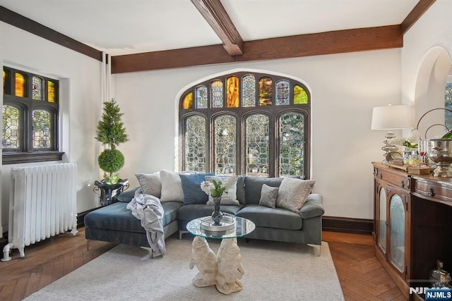 living room with radiator, beamed ceiling, healthy amount of natural light, and arched walkways