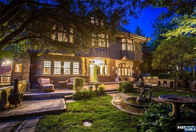 back of house at night with brick siding and an outdoor hangout area