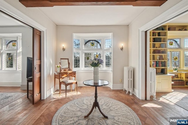 living area featuring radiator heating unit, plenty of natural light, and baseboards
