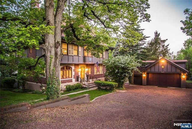 english style home with an attached garage, asphalt driveway, and brick siding