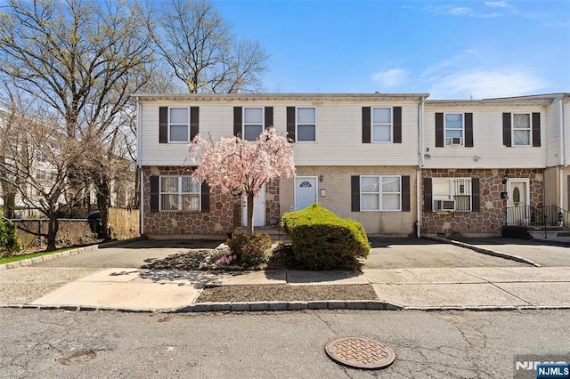 townhome / multi-family property with stone siding and cooling unit