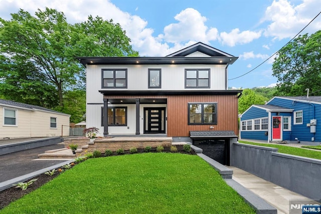 contemporary house with a porch, a garage, and a front yard