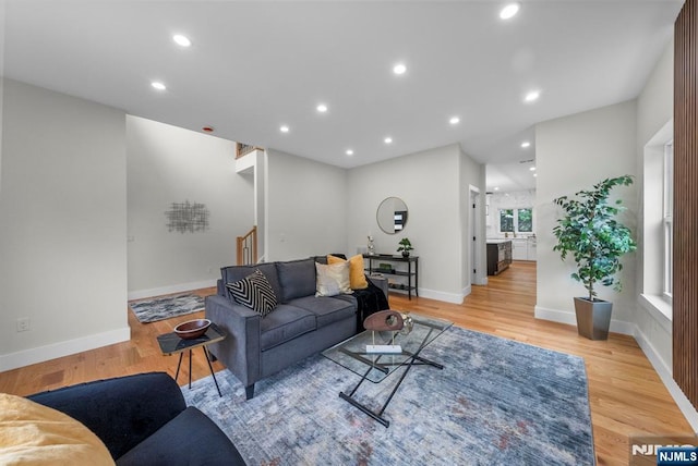 living room with light wood-style floors, baseboards, recessed lighting, and stairs