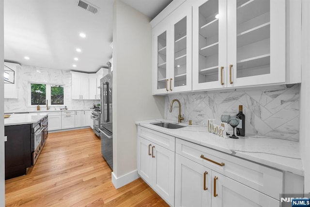 kitchen featuring a sink, white cabinetry, decorative backsplash, recessed lighting, and light stone countertops