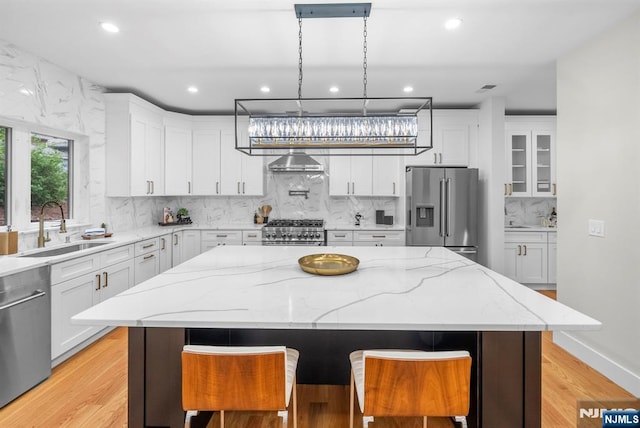 kitchen with stainless steel appliances, a sink, white cabinets, recessed lighting, and a center island