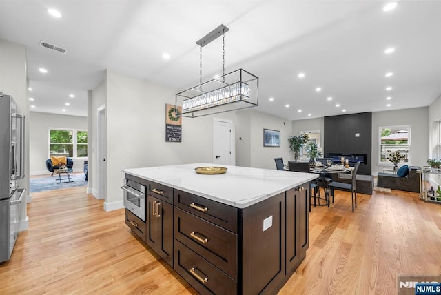 kitchen with light wood finished floors, a kitchen island, dark brown cabinetry, recessed lighting, and baseboards
