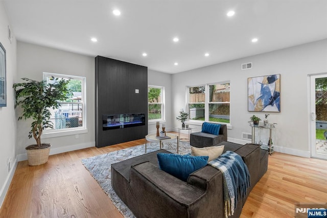living area with wood finished floors, recessed lighting, baseboards, and a fireplace