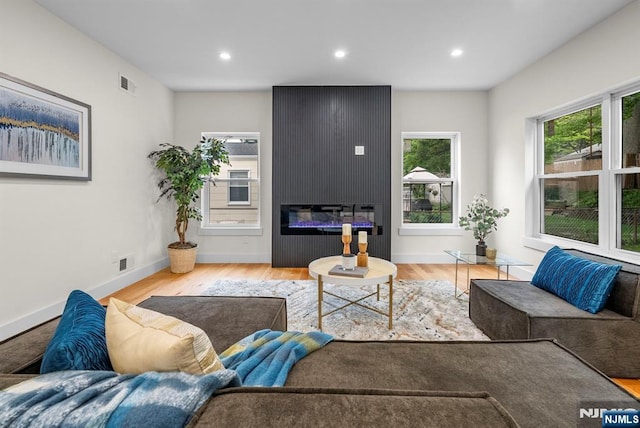 living room with plenty of natural light, wood finished floors, recessed lighting, baseboards, and a large fireplace
